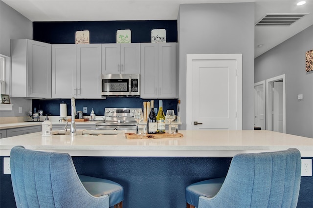 kitchen with appliances with stainless steel finishes, a kitchen island with sink, and a breakfast bar area