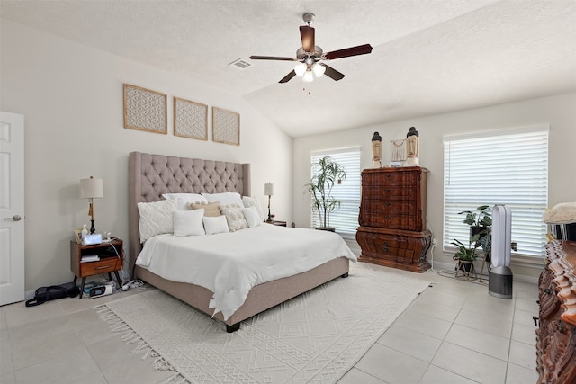 tiled bedroom with ceiling fan, a textured ceiling, and vaulted ceiling