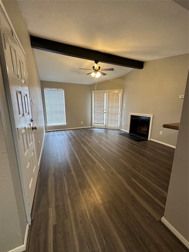 unfurnished living room with ceiling fan, beam ceiling, dark hardwood / wood-style floors, and a textured ceiling