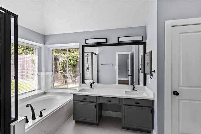 bathroom featuring tile patterned floors, vanity, a bath, and a textured ceiling