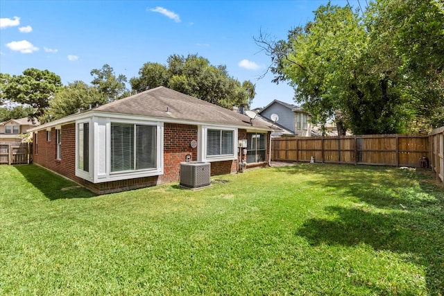 rear view of property featuring a yard and central air condition unit