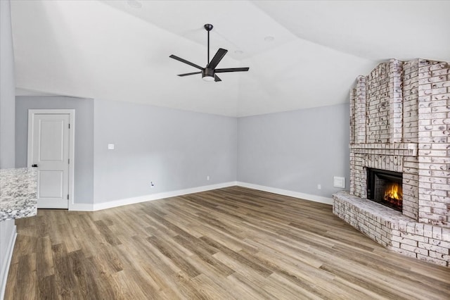 unfurnished living room with ceiling fan, a fireplace, lofted ceiling, and light wood-type flooring