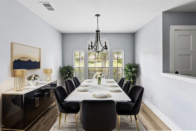 dining space with hardwood / wood-style flooring and a notable chandelier