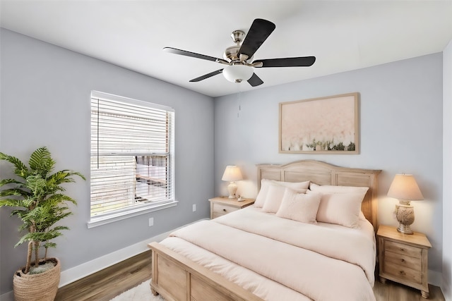 bedroom featuring multiple windows, hardwood / wood-style flooring, and ceiling fan