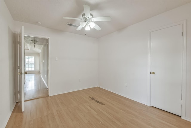 spare room with light wood-style floors, visible vents, baseboards, and a ceiling fan