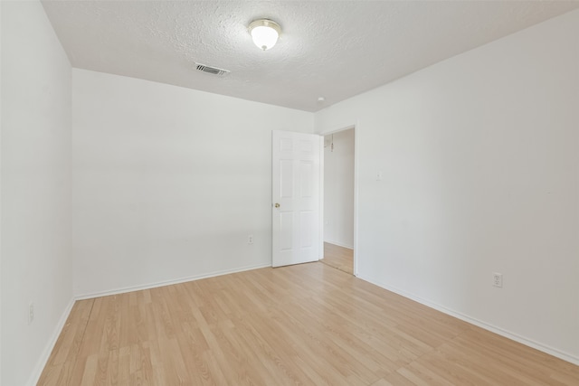 unfurnished room featuring light wood-type flooring and a textured ceiling