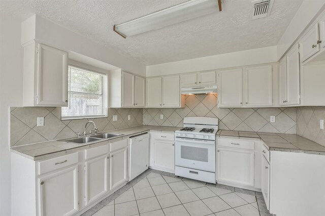 kitchen with sink, white appliances, decorative backsplash, and white cabinets