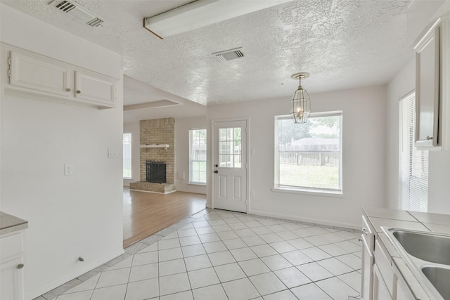 interior space with visible vents, a fireplace, a notable chandelier, and light tile patterned floors