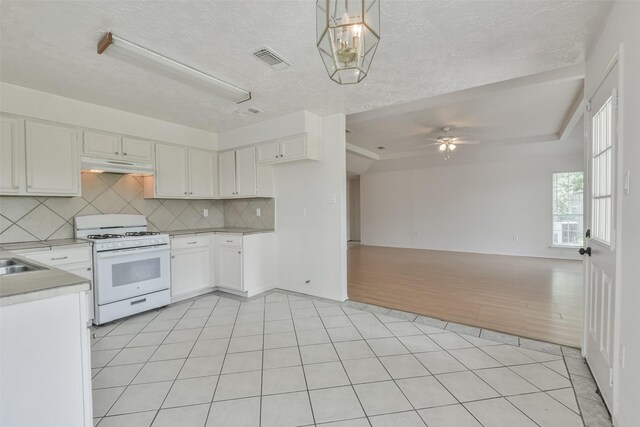 kitchen with light hardwood / wood-style floors, tasteful backsplash, ceiling fan, and white range with gas cooktop