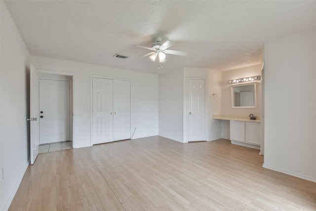 unfurnished bedroom featuring light wood finished floors, visible vents, ceiling fan, a textured ceiling, and baseboards