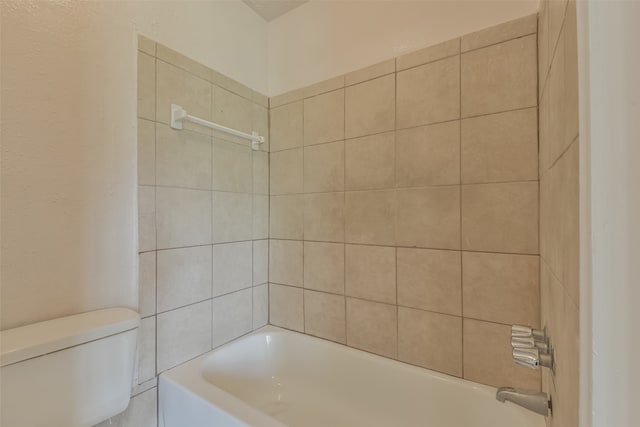 bathroom featuring tiled shower / bath combo and toilet