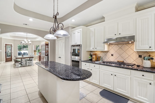 kitchen with appliances with stainless steel finishes, white cabinets, backsplash, and a tray ceiling