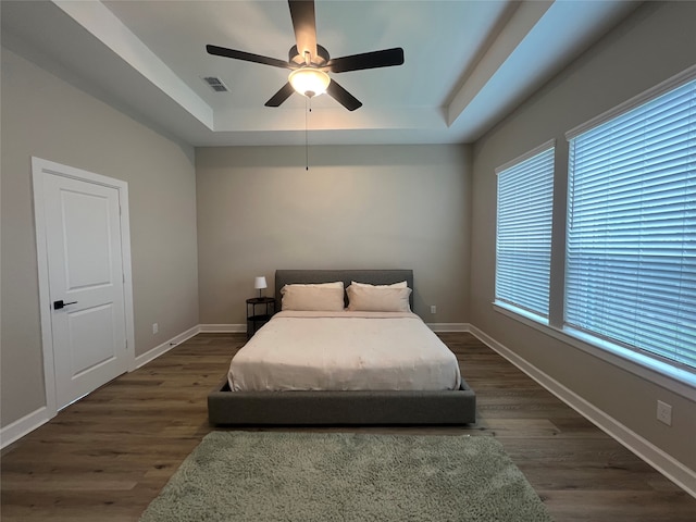 bedroom featuring dark hardwood / wood-style flooring, multiple windows, and ceiling fan