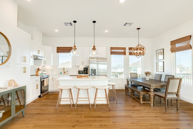 kitchen with appliances with stainless steel finishes, light hardwood / wood-style flooring, a wealth of natural light, and tasteful backsplash