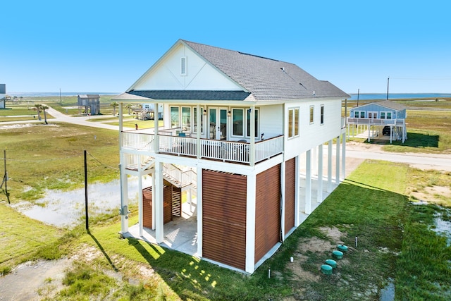 back of house with covered porch, a carport, and a yard