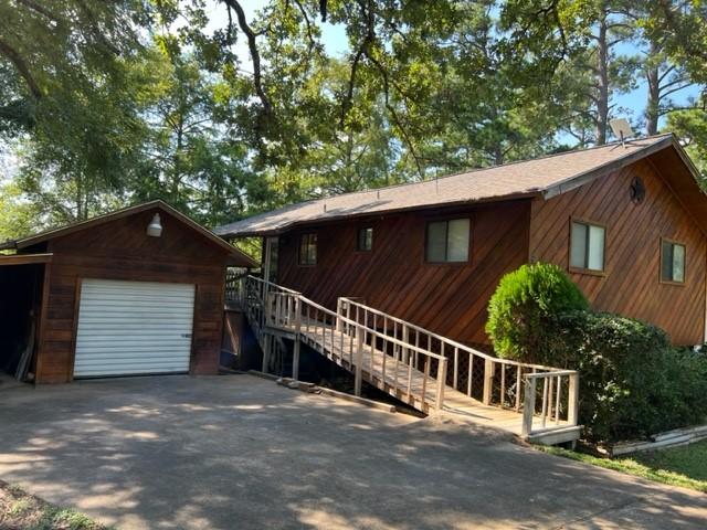 view of front of property with stairs, a detached garage, aphalt driveway, and an outbuilding