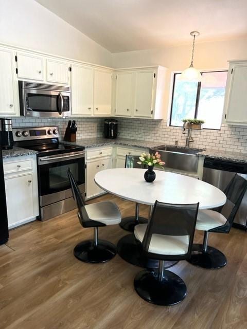 kitchen with white cabinets, sink, appliances with stainless steel finishes, tasteful backsplash, and decorative light fixtures