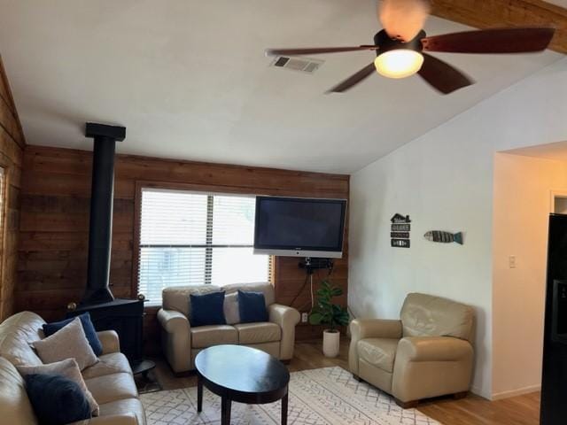 living room featuring wooden walls, light hardwood / wood-style floors, and vaulted ceiling