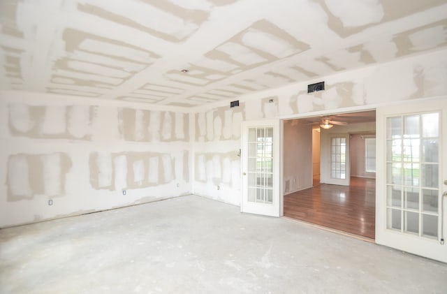 unfurnished room with ceiling fan, concrete floors, and french doors