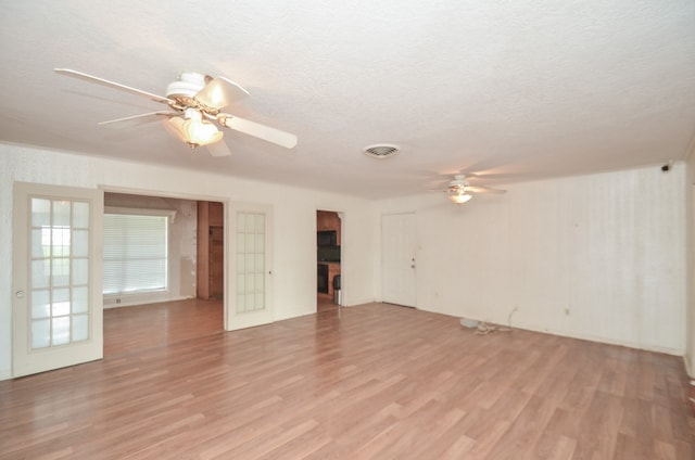 unfurnished living room featuring ceiling fan, light wood-type flooring, and a textured ceiling