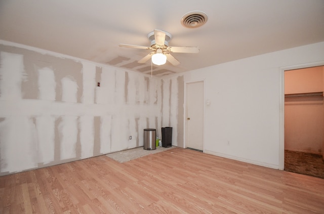 interior space with light hardwood / wood-style floors, a walk in closet, ceiling fan, and a closet