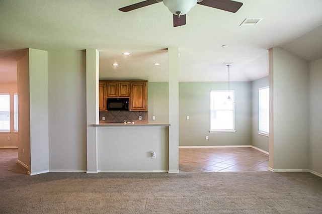 kitchen featuring ceiling fan, a wealth of natural light, tasteful backsplash, and light carpet