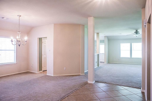 carpeted empty room featuring a wealth of natural light and ceiling fan with notable chandelier