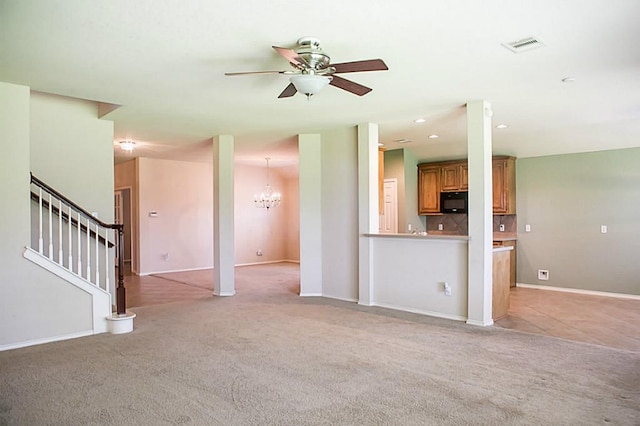 unfurnished living room with ceiling fan with notable chandelier and light colored carpet