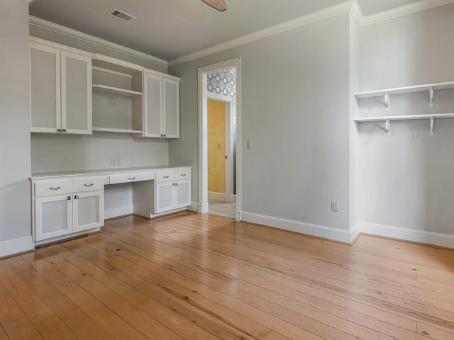 unfurnished office featuring ornamental molding, light wood-type flooring, built in study area, and visible vents