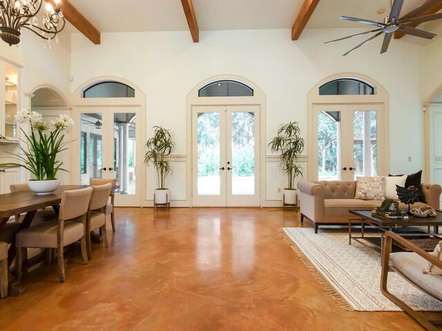 interior space with concrete floors, french doors, ceiling fan with notable chandelier, high vaulted ceiling, and beam ceiling