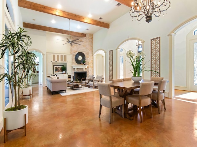 dining area featuring concrete flooring, arched walkways, a fireplace, and a high ceiling