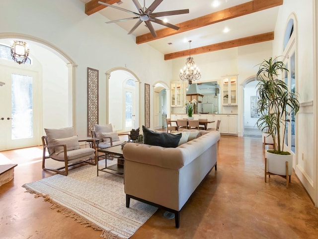 living area with a chandelier, beamed ceiling, a high ceiling, and concrete floors