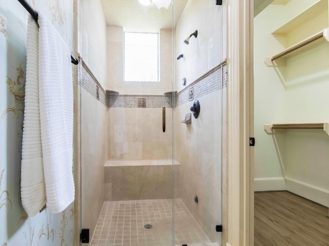 full bath with a stall shower, baseboards, and wood finished floors