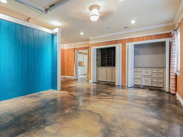 interior space featuring wood walls, ceiling fan, and ornamental molding