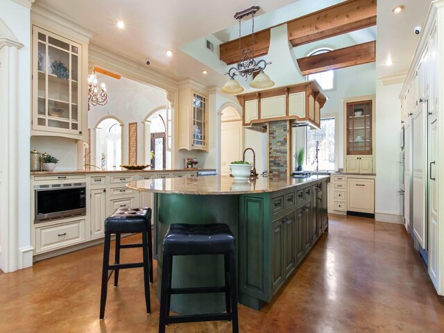 kitchen featuring oven, decorative light fixtures, concrete flooring, a center island with sink, and a chandelier