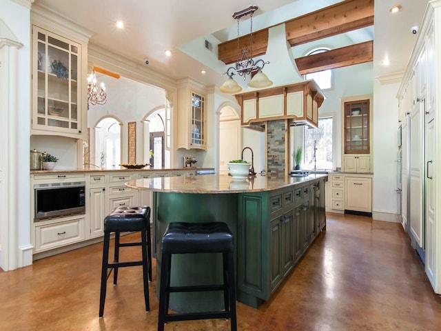 kitchen featuring a kitchen island with sink, concrete floors, a chandelier, and beamed ceiling