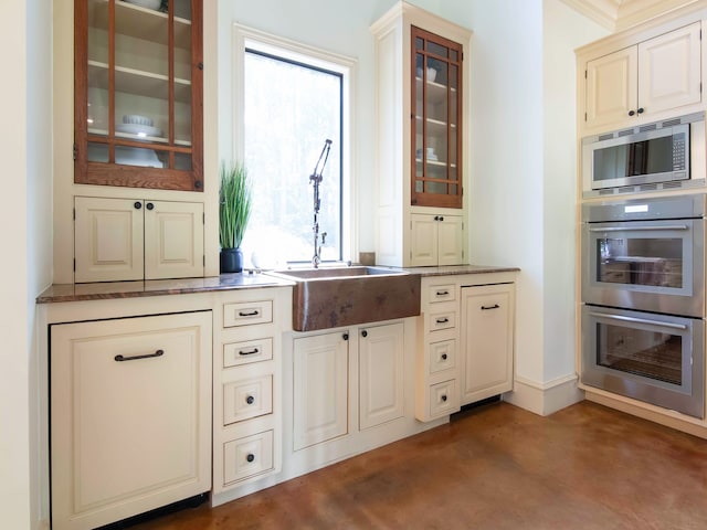 kitchen with appliances with stainless steel finishes, cream cabinets, sink, and a healthy amount of sunlight