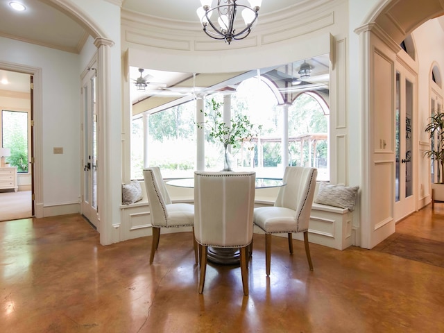 dining space with concrete flooring, a notable chandelier, and ornamental molding