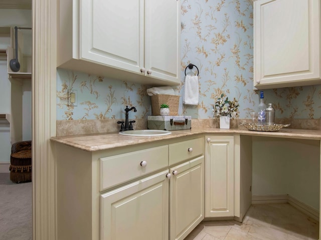 kitchen with light countertops, a sink, baseboards, and wallpapered walls