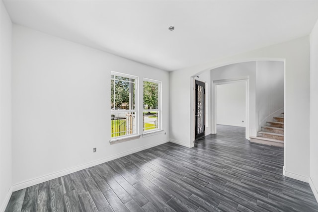 16518 Boston Post Rd, Cypress, TX 77429 - empty room with arched walkways, dark wood-style flooring, and stairway