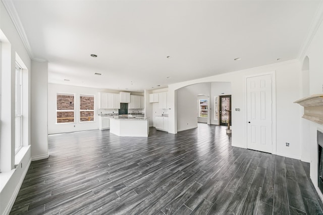 16518 Boston Post Rd, Cypress, TX 77429 - unfurnished living room featuring arched walkways, dark wood-style flooring, a fireplace, and crown molding