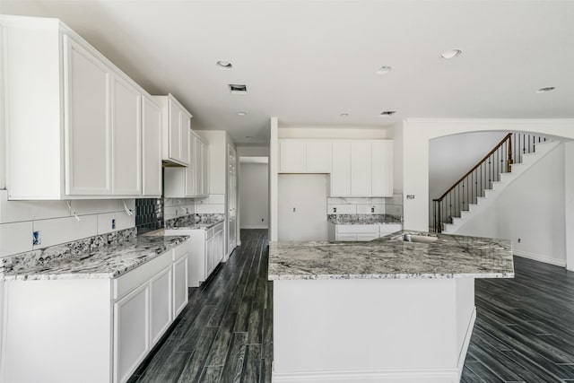 16518 Boston Post Rd, Cypress, TX 77429 - kitchen with dark wood-type flooring, white cabinetry, an island with sink, backsplash, and light stone countertops