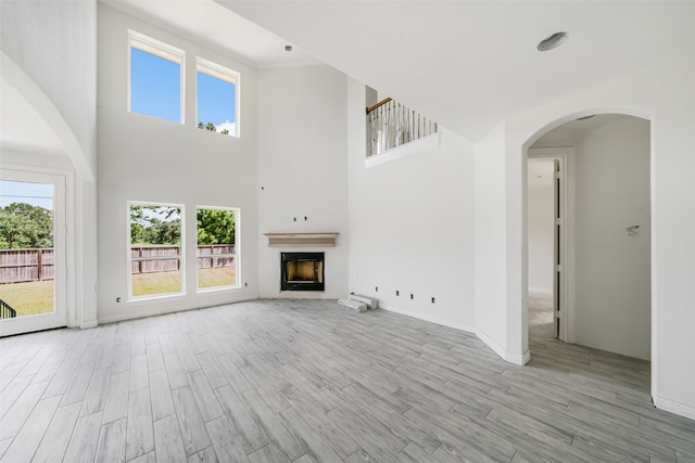 unfurnished living room with light wood-type flooring and a high ceiling