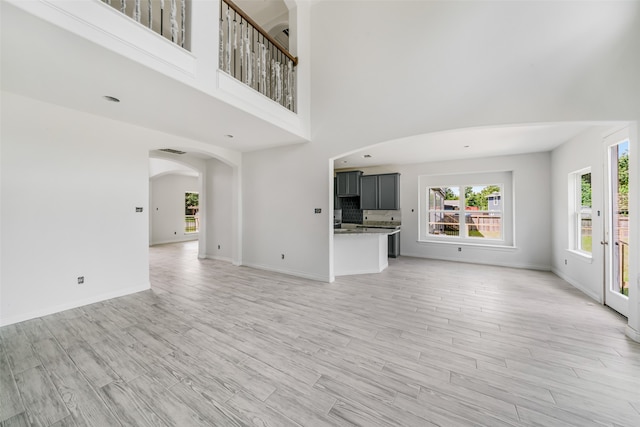 unfurnished living room featuring light hardwood / wood-style floors and a high ceiling