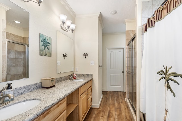 bathroom with crown molding, hardwood / wood-style floors, dual bowl vanity, and walk in shower