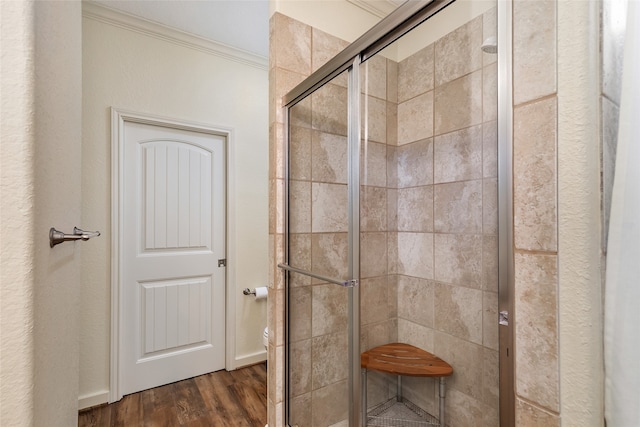 bathroom with a shower with shower door, hardwood / wood-style floors, and ornamental molding