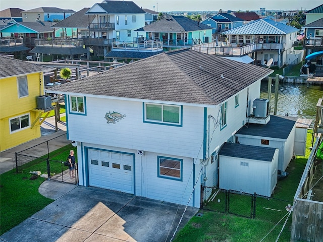 exterior space featuring a water view, a balcony, cooling unit, a garage, and a front lawn