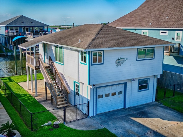 exterior space featuring a garage, a front lawn, and a water view