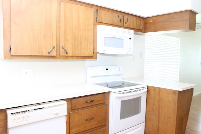 kitchen with wood-type flooring, white appliances, and kitchen peninsula