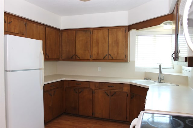 kitchen with sink, stove, white fridge, and dark hardwood / wood-style flooring